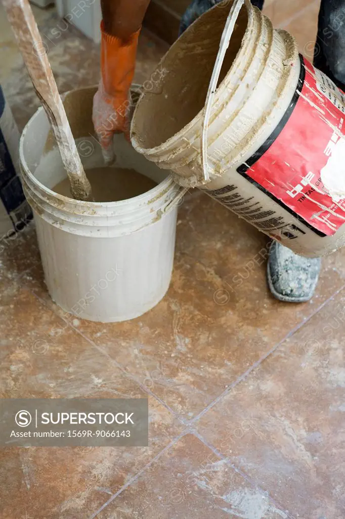 Worker pouring plaster from one bucket to another