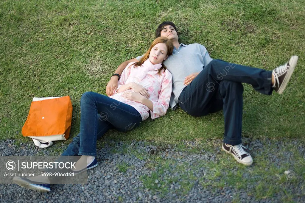 Young couple lying together on grass, high angle view