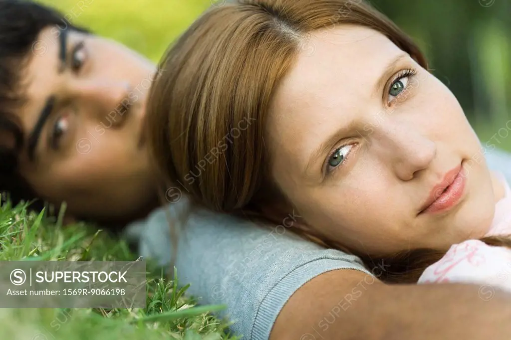 Young couple lying on grass, looking at camera, close_up