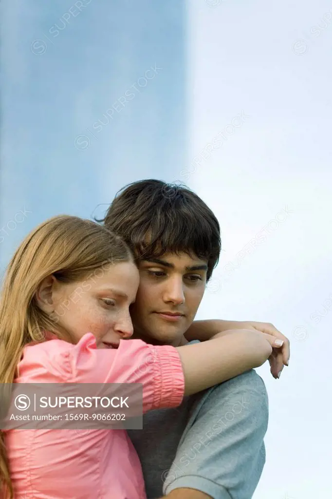 Young couple embracing, looking down