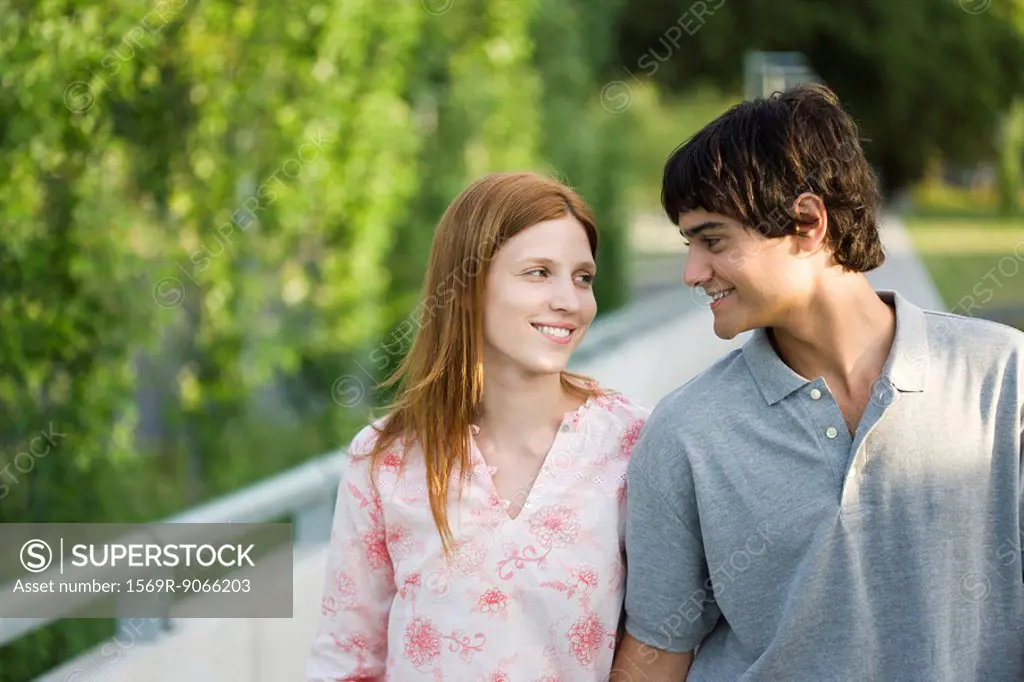 Young couple walking together outdoors, smiling at each other