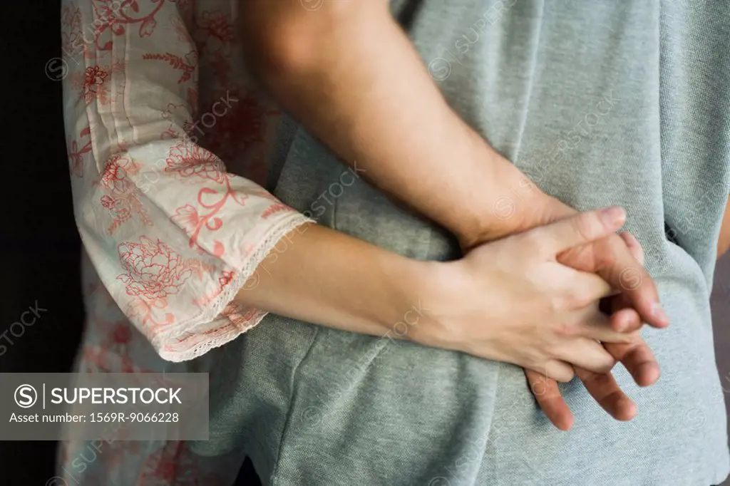 Couple embracing, holding hands, cropped