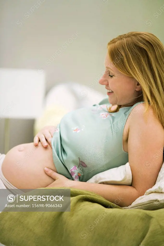 Pregnant woman relaxing, hand on belly
