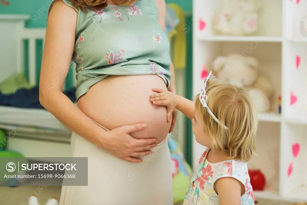 Little girl touching mother´s pregnant belly