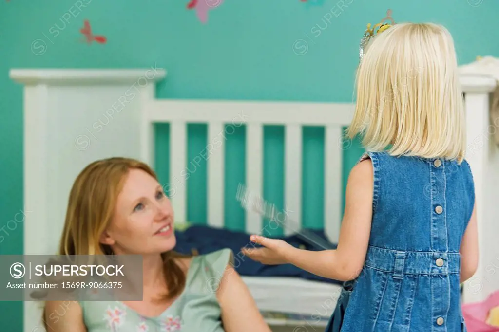Little girl playing with mother in bedroom