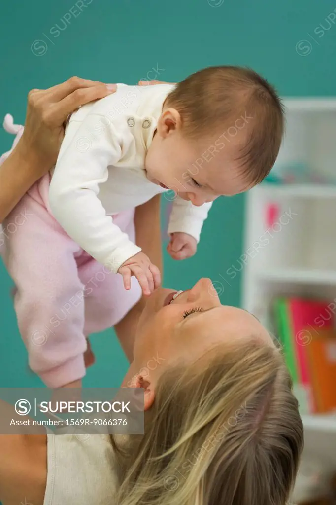 Young mother holding up baby, both smiling