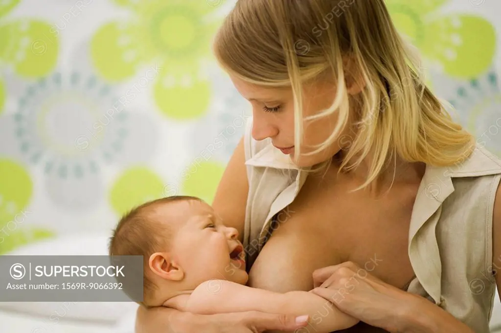 Young mother trying to breast feed crying baby