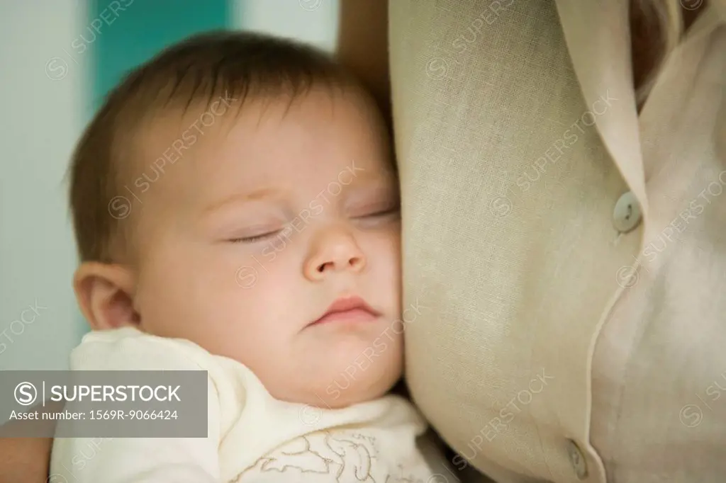 Baby sleeping against mother´s chest, close_up