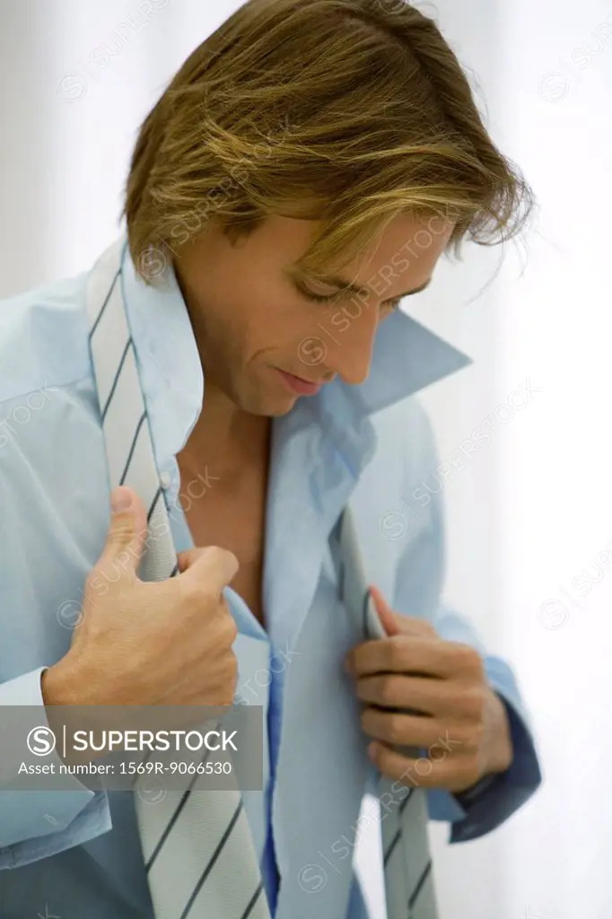 Man getting dressed, putting on tie