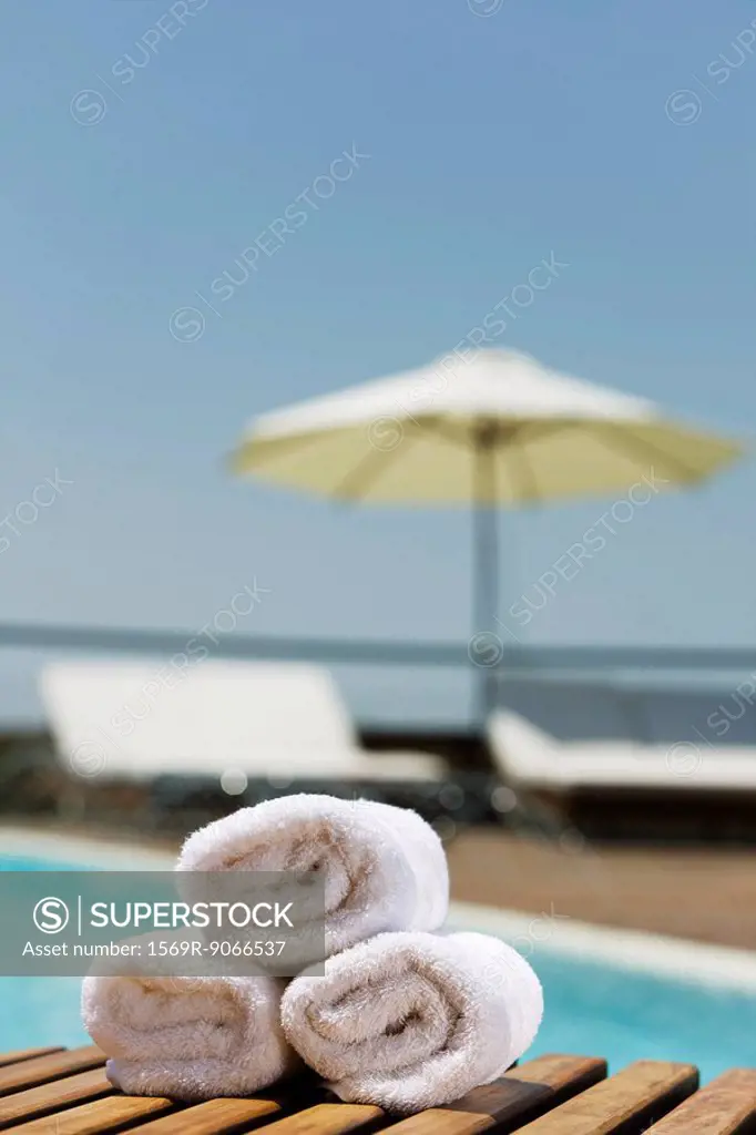 Fresh towels rolled and stacked on poolside table