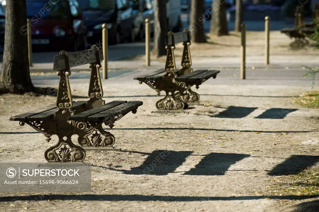 Ornate park benches casting shadows on ground