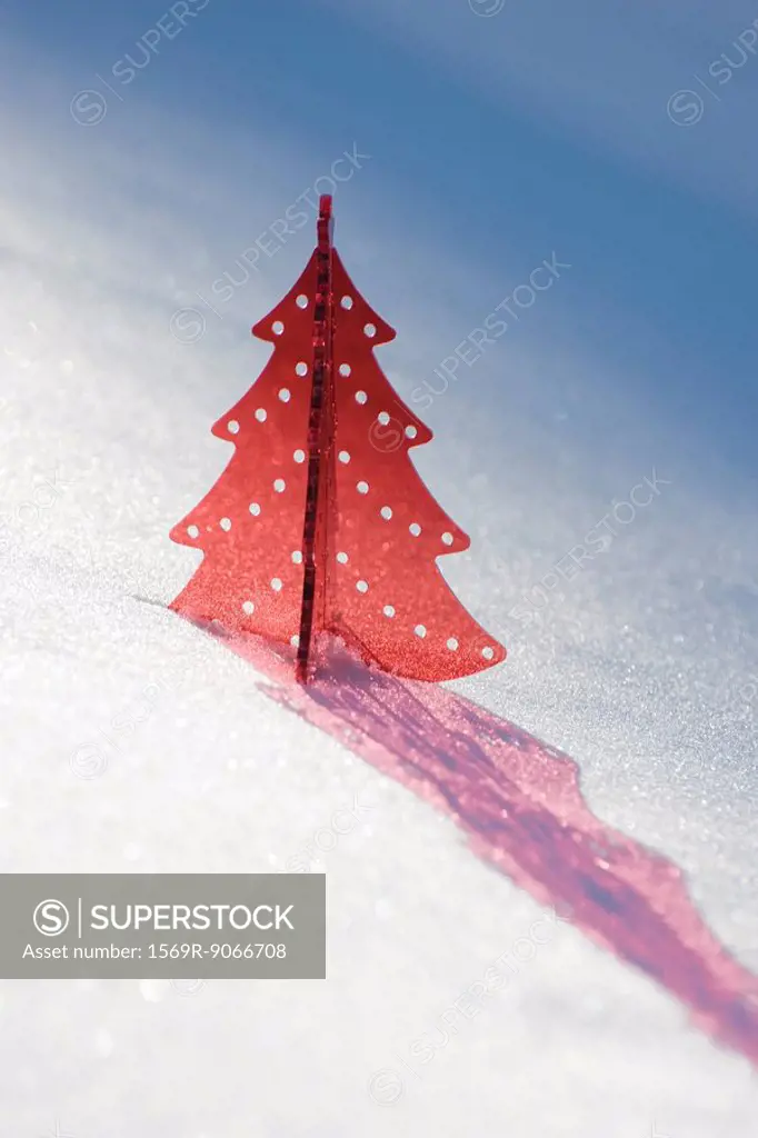 Red plastic Christmas tree decoration set in snow casting shadow