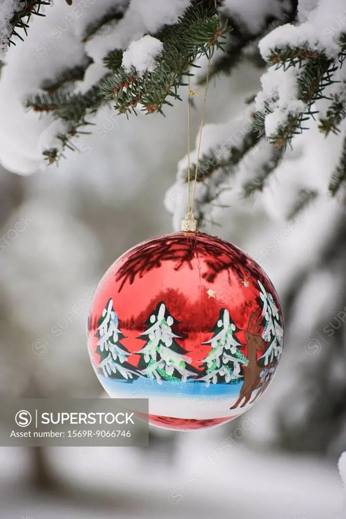 Colorful Christmas ornament hanging from snow_covered branch