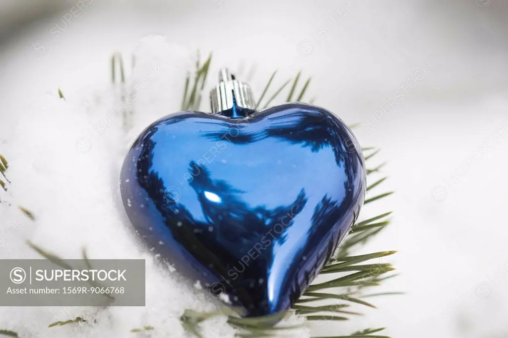 Heart shaped Christmas ornament on snow_covered evergreen branch
