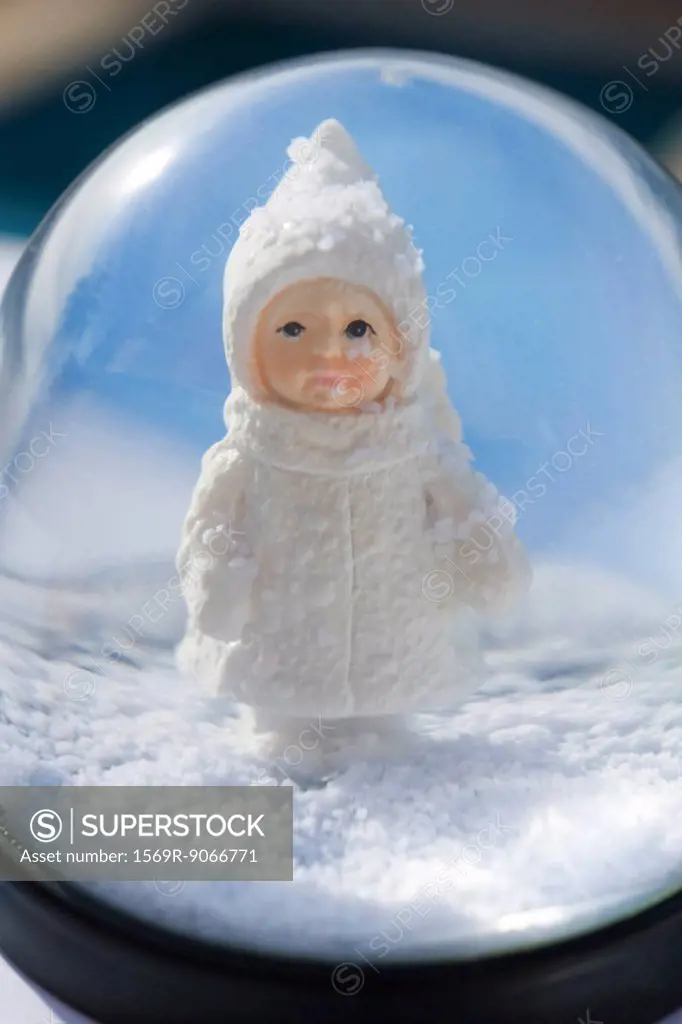 Snow globe, figurine of little girl wearing winter coat and hat looking out