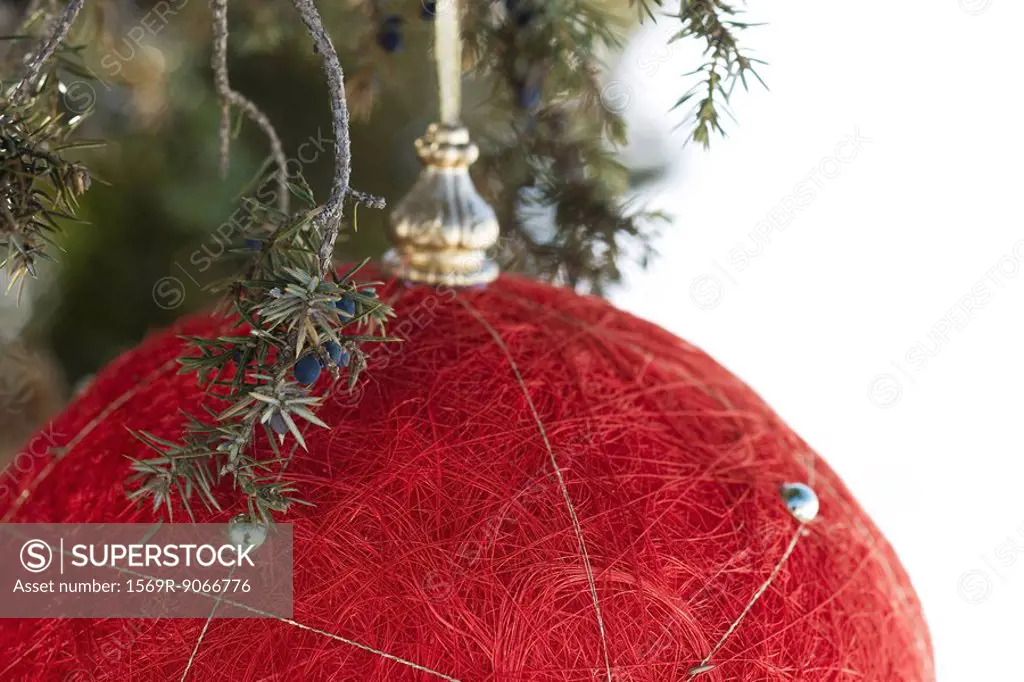Red Christmas ornament hanging from evergreen branch, close_up