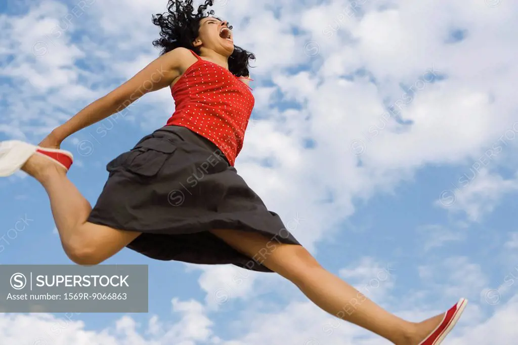 Young woman jumping in midair, low angle view