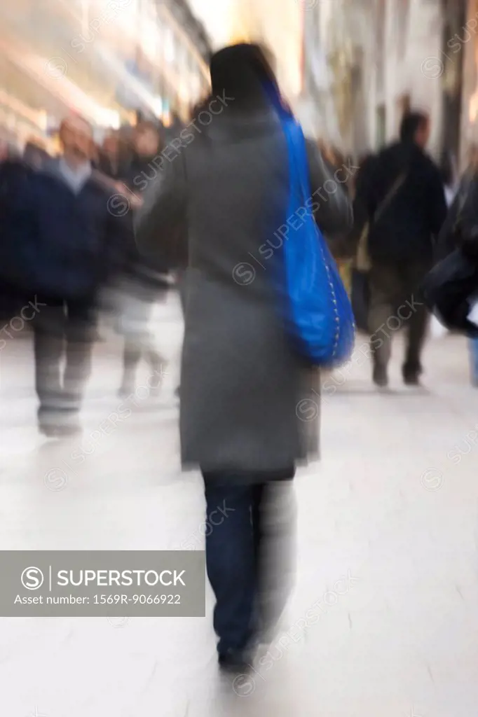 Pedestrians walking on sidewalk, rear view, blurred