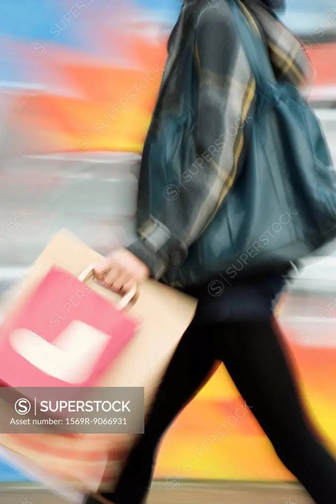 Shopper walking with shopping bags, blurred