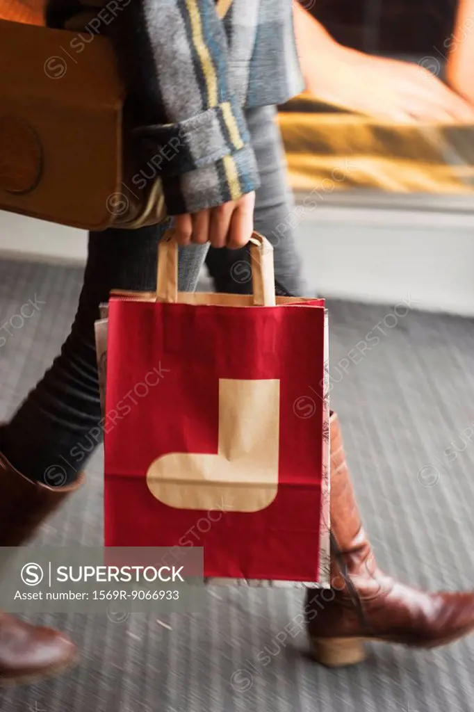 Shopper carrying shopping bag with Christmas stocking on it, cropped