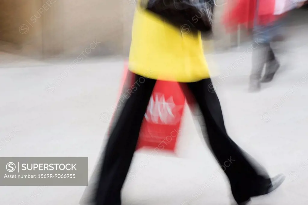 Pedestrian carrying shopping bag, cropped