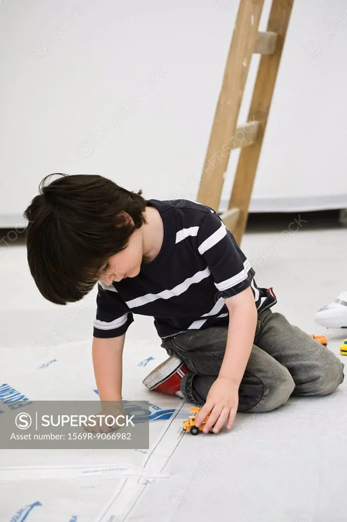 Little boy playing with toy truck on floor