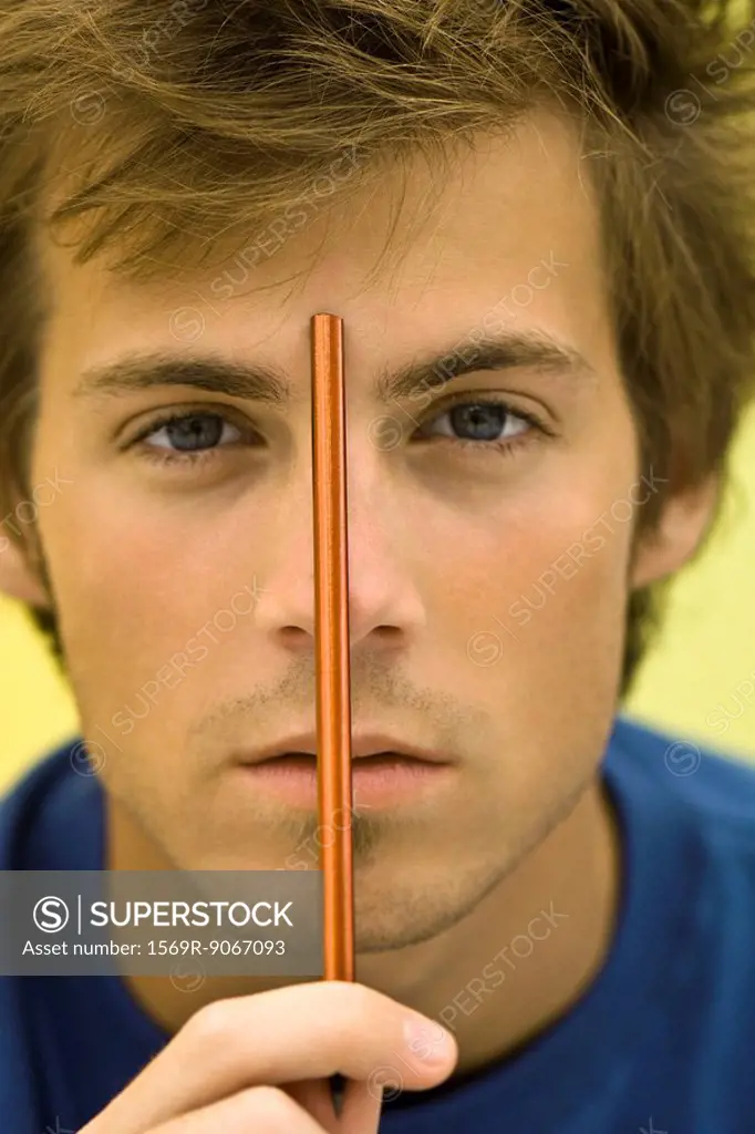 Young man holding pencil up to forehead