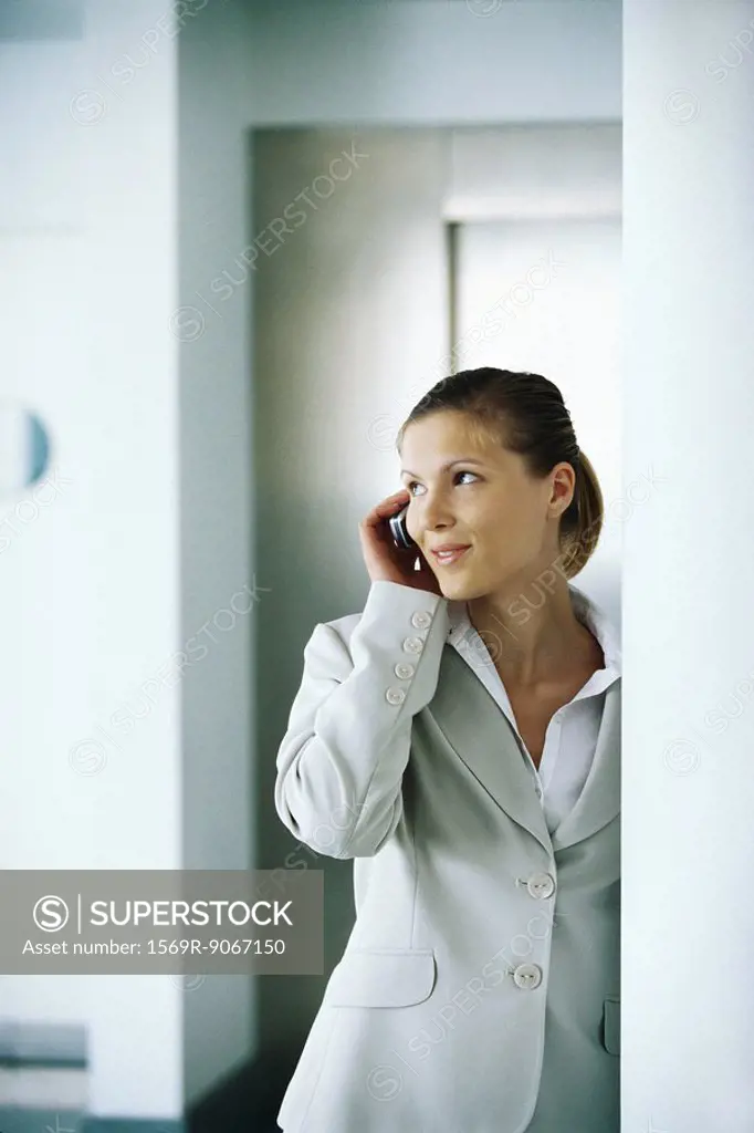 Businesswoman using cell phone, glancing away