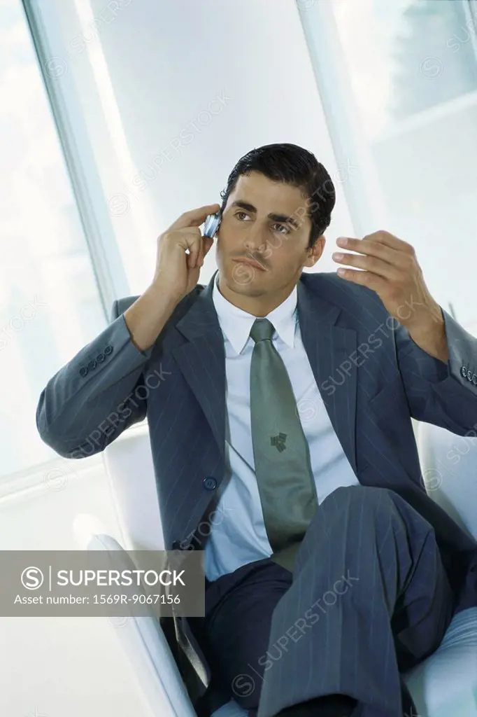 Businessman sitting with legs crossed, using cell phone