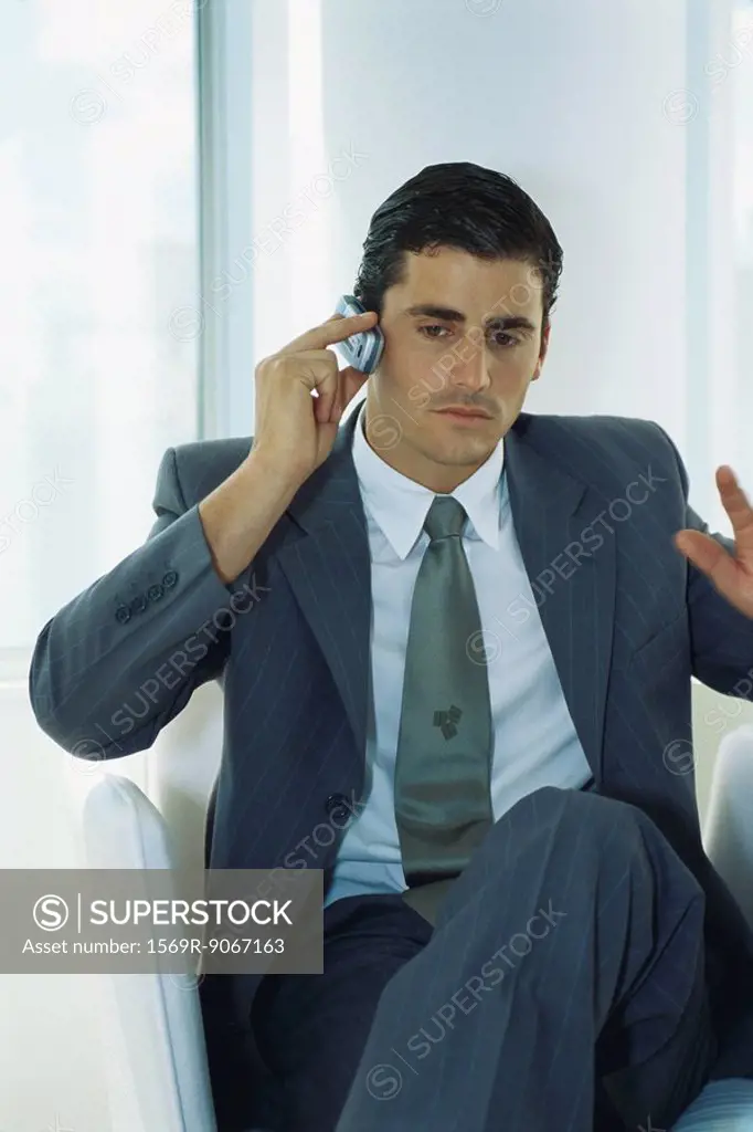 Businessman sitting with legs crossed using cell phone