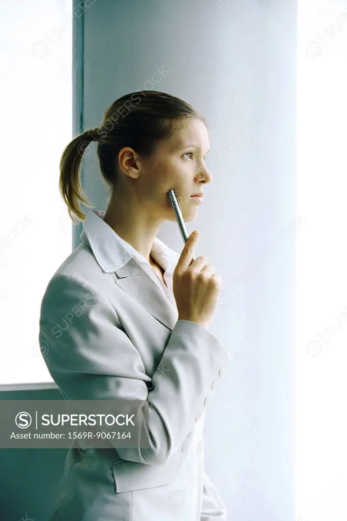 Businesswoman waiting by column, looking away contemplatively
