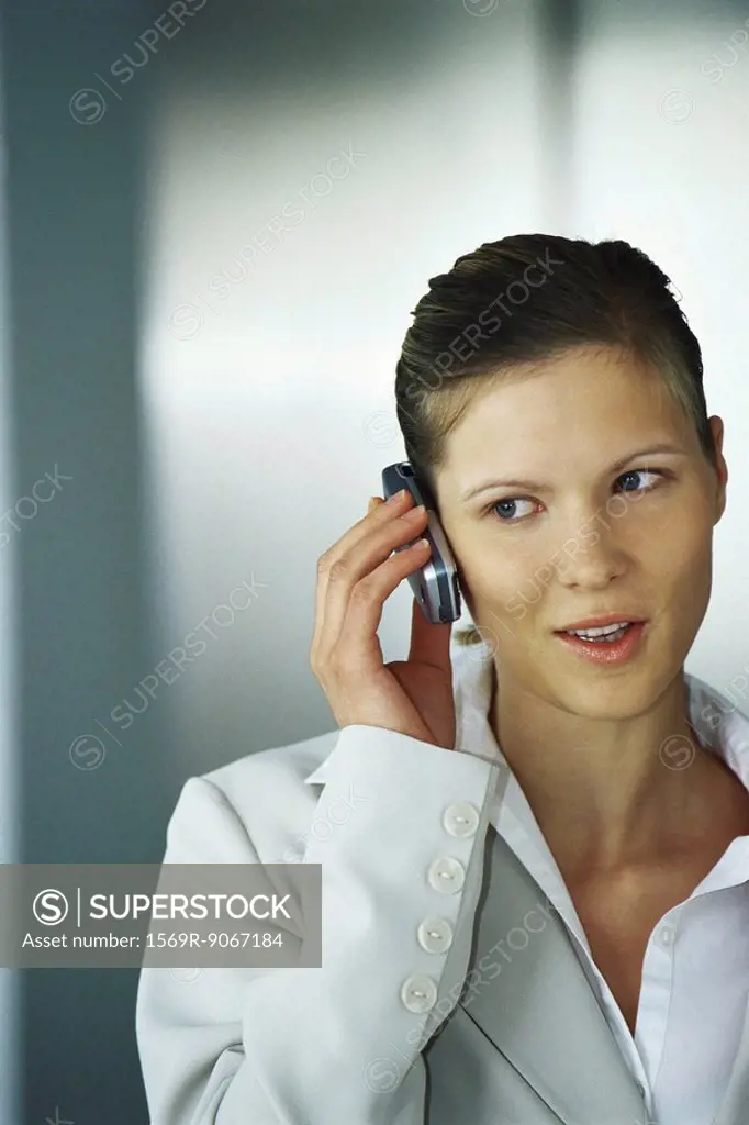 Businesswoman using cell phone, glancing sideways