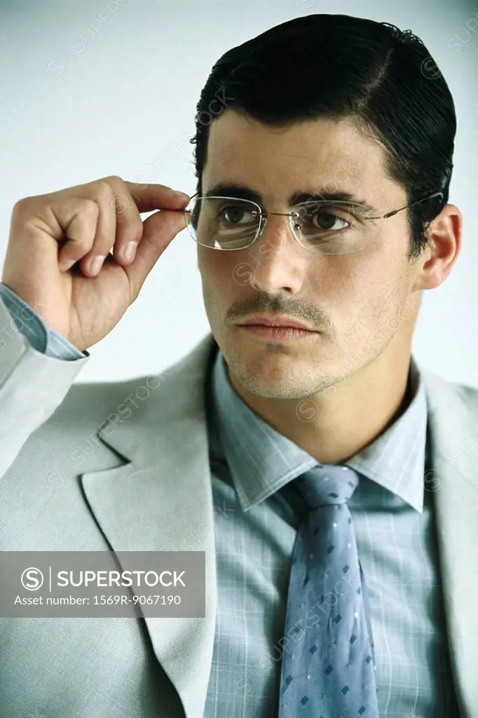 Businessman adjusting glasses, portrait