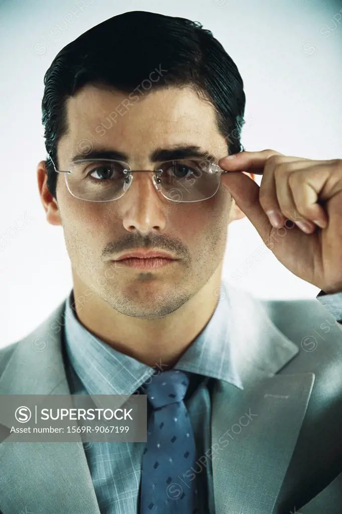 Businessman looking at camera, adjusting glasses, portrait
