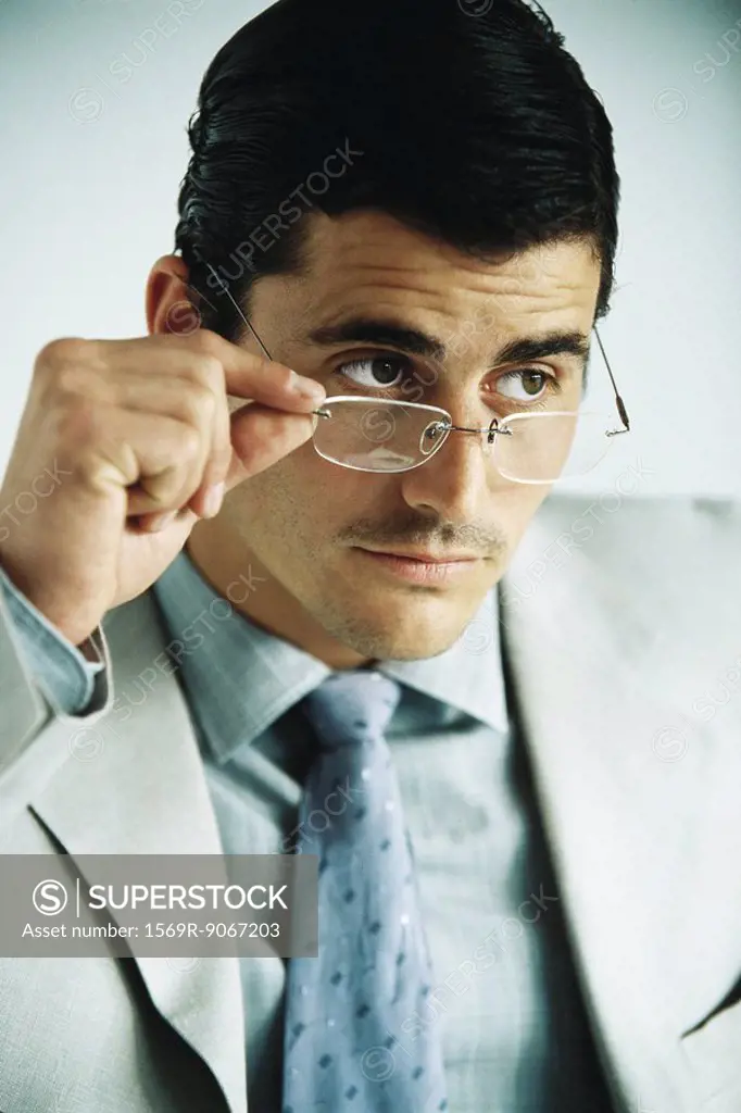 Businessman looking away, lowering glasses, portrait