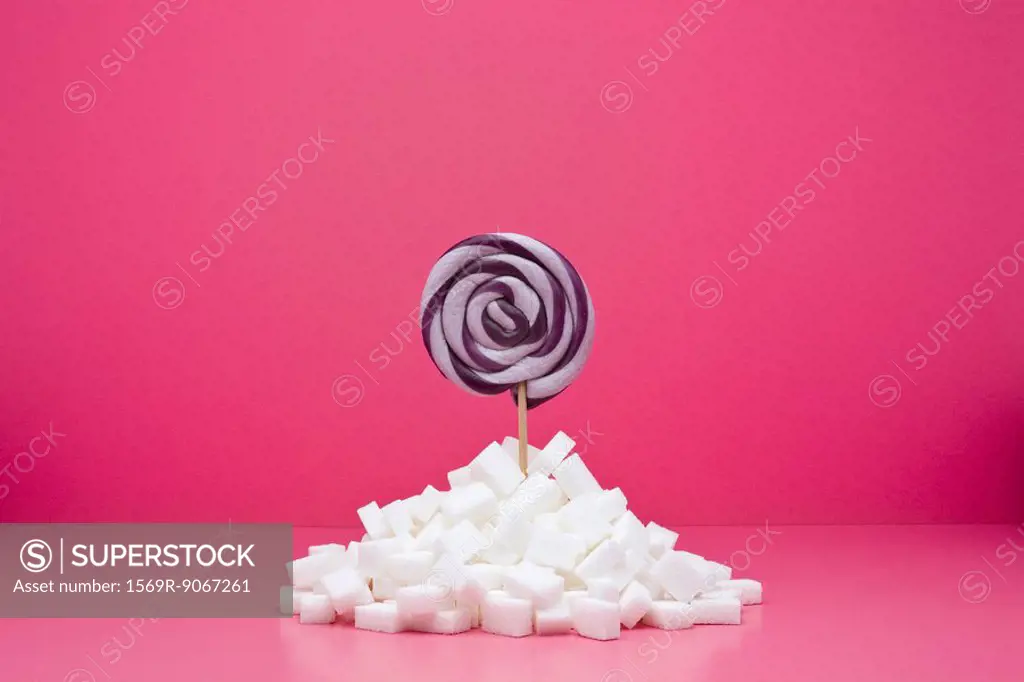 Food concept, lollipop sticking out from pile of sugar cubes