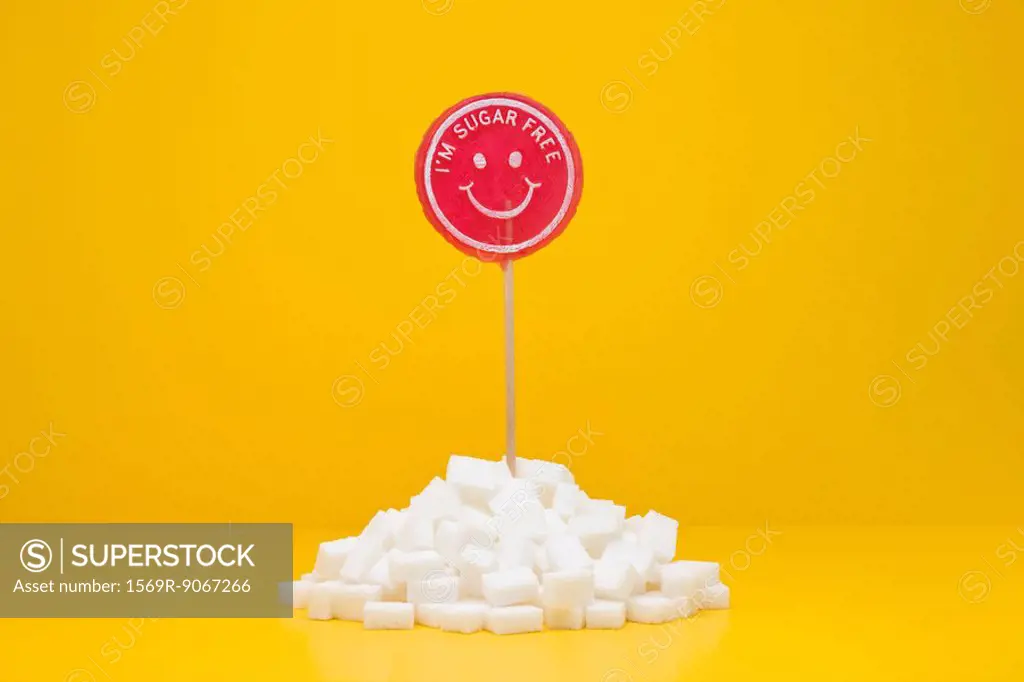 Food concept, sugar_free lollipop sticking out of pile of sugar cubes