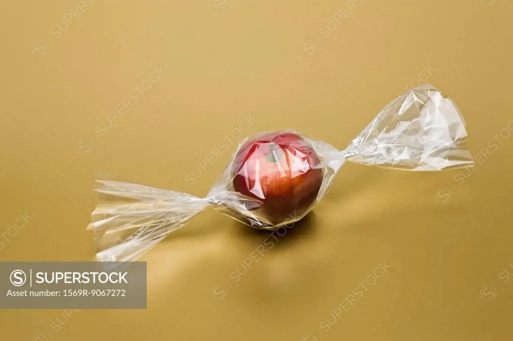 Food concept, fresh apple inside cellophane candy wrapper