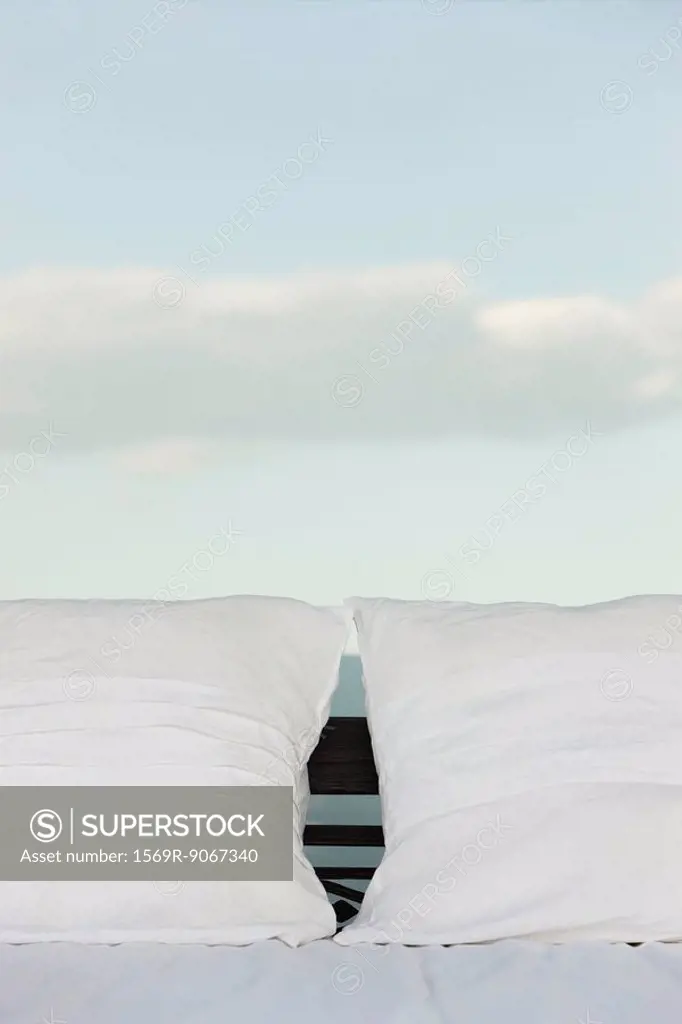 Pillows on bed, clouds in background