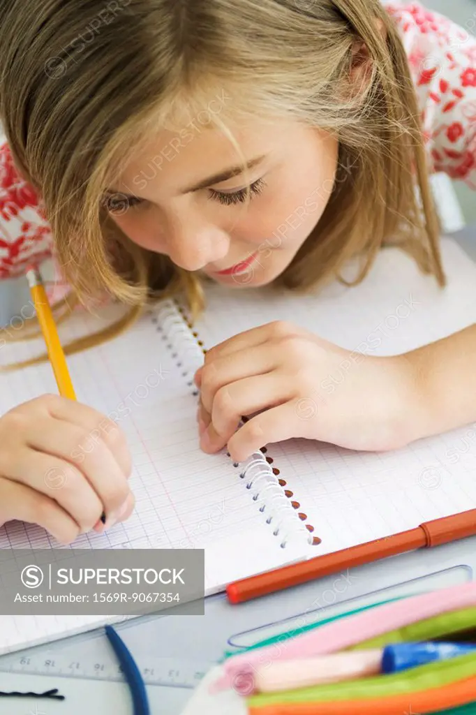 Girl writing in notebook, high angle view