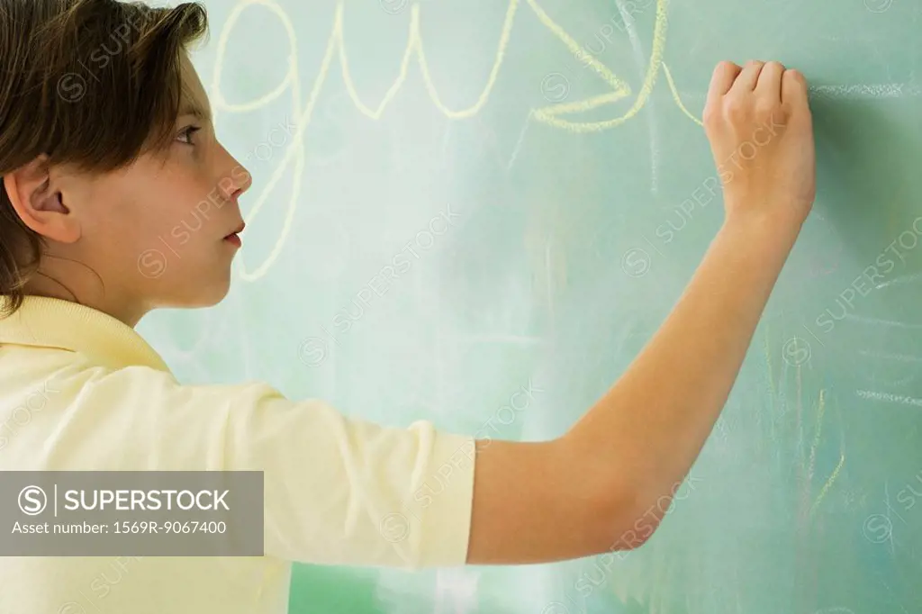 Boy writing in cursive on blackboard