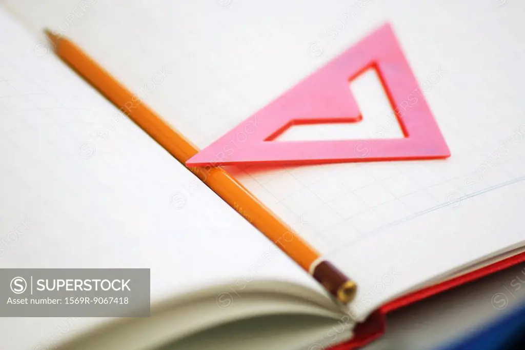 Pencil and triangle resting on notebook