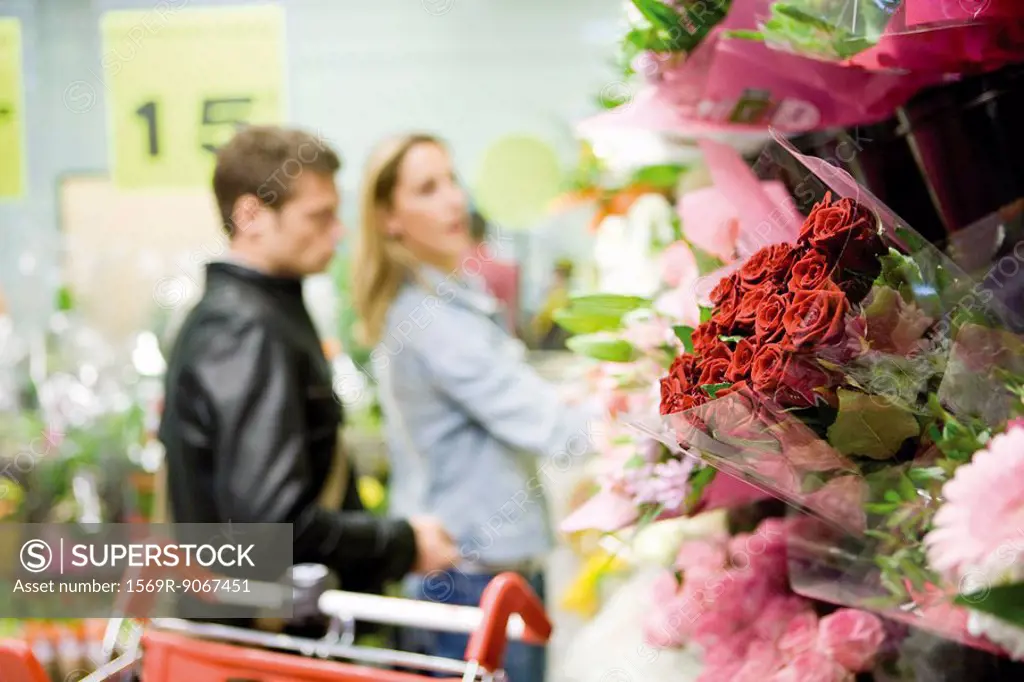 Flower bouquets at flower shop, couples browsing in background