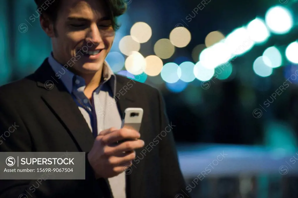 Man text messaging outdoors at night