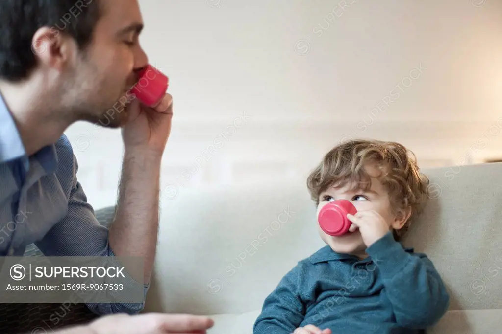 Father and toddler son pretending to drink tea with toy tea cups