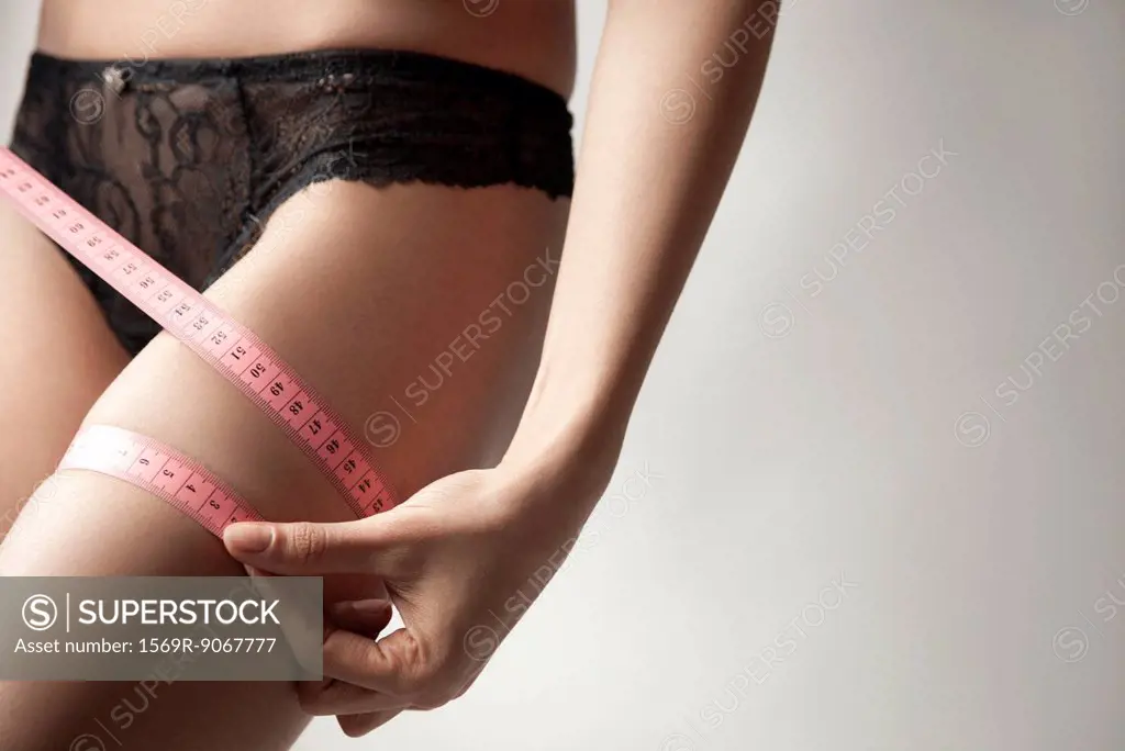 Woman measuring her thigh with measuring tape