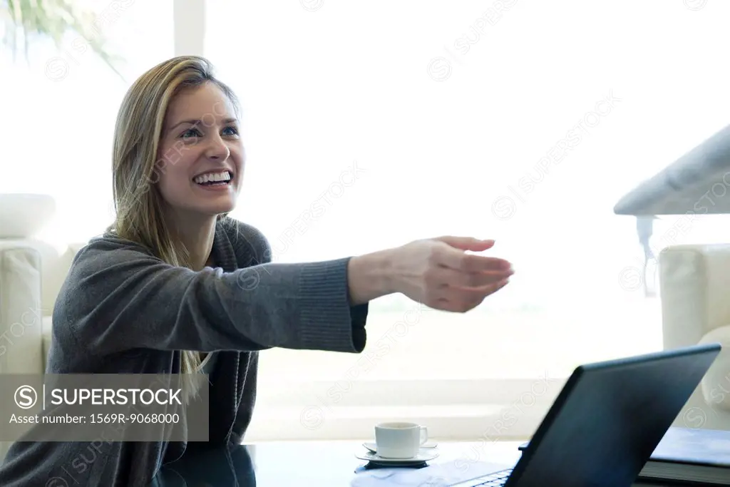 Woman reaching for paper being handed to her by person out_of_frame