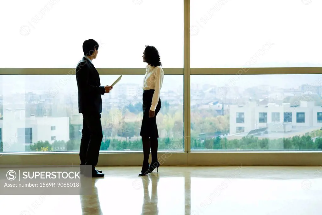Executives standing by window talking