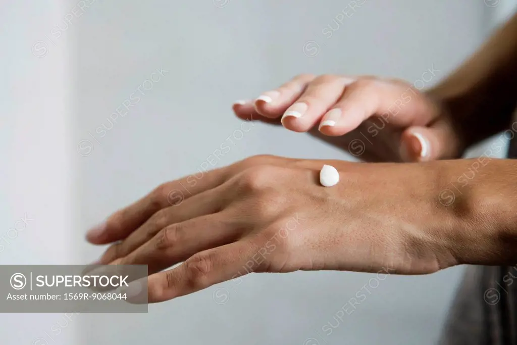 Woman moisturizing hands, cropped