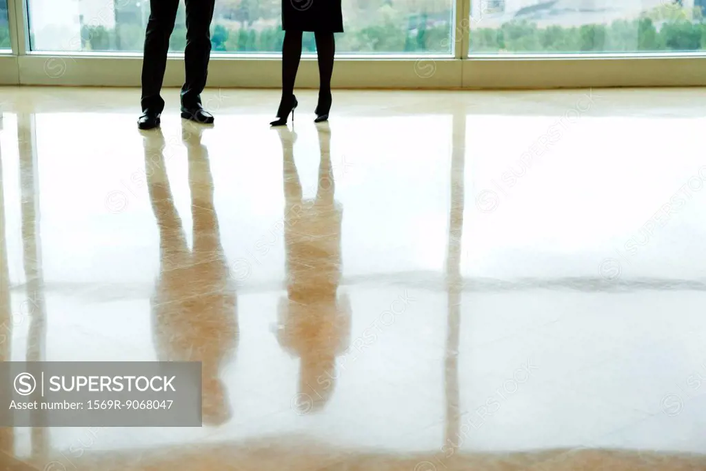 Businessman and businesswoman standing in lobby, low section